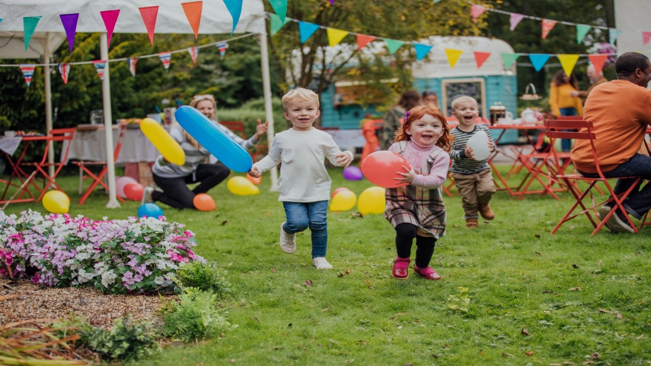 Fundacja ORLEN. przyjęcie w ogrodzie, grupa dzieci z balonami biegnie przed siebie