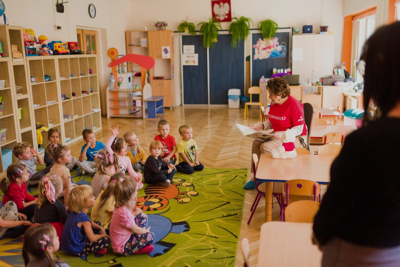 ORLEN Fundacja. Wolontariuszka czyta książkę dzieciom w przedszkolu